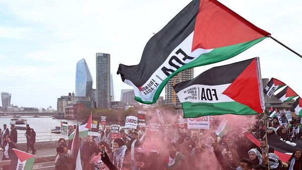 أشخاص يرفعون لافتات ويلوحون بالأعلام الفلسطينية أثناء عبورهم جسر واترلو خلال مسيرة من أجل فلسطين في لندن، 28 أكتوبر/ تشرين الأول 2023 - سبوتنيك عربي