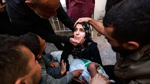 امرأة تحمل جثة طفلتها التي قُتلت في غارة إسرائيلية على رفح بجنوب قطاع غزة، في باحة مستشفى النجار في 1 ديسمبر 2023 - سبوتنيك عربي