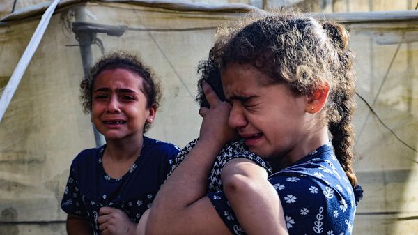 أطفال فلسطينيون يبكون على عائلتهم التي قُتلت في قصف إسرائيلي على رفح في جنوب قطاع غزة - سبوتنيك عربي