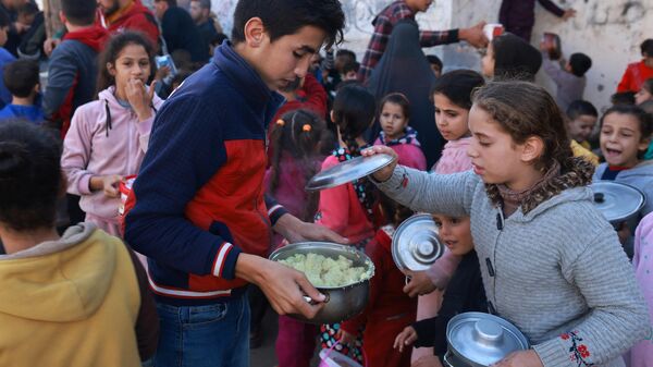 أطفال فلسطينيون يجمعون الطعام في نقطة تبرع  في مدينة رفح جنوب قطاع غزة، في 6 ديسمبر 2023، - سبوتنيك عربي