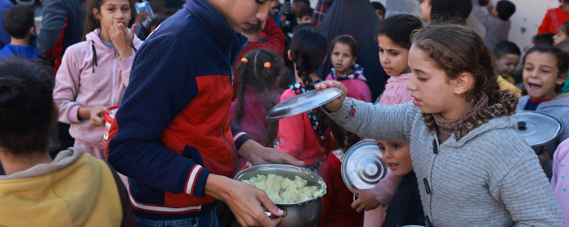 أطفال فلسطينيون يجمعون الطعام في نقطة تبرع  في مدينة رفح جنوب قطاع غزة، في 6 ديسمبر 2023، - سبوتنيك عربي, 1920, 13.03.2024