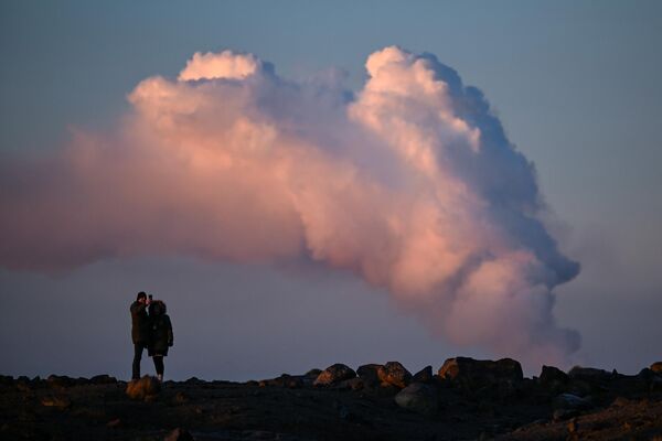 الناس يشاهدون الدخان المتصاعد أثناء ثوران بركاني شمال مدينة غريندافيك، جنوب غربي أيسلندا، في 14 يناير 2024. - سبوتنيك عربي