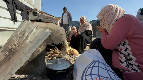 A displaced Palestinian makes bread on an old clay oven to feed her family and help the displaced - Sputnik Arabic