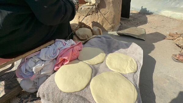 A displaced Palestinian makes bread on an old clay oven to feed her family and help the displaced - Sputnik Arabic