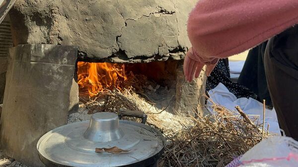 A displaced Palestinian makes bread on an old clay oven to feed her family and help the displaced - Sputnik Arabic