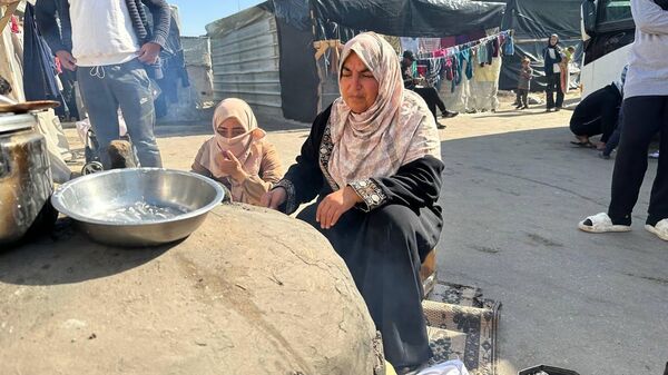 A displaced Palestinian makes bread on an old clay oven to feed her family and help the displaced - Sputnik Arabic