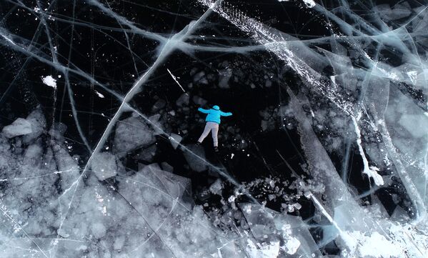 فتاة تستلقي على جليد نهر ينيسي في منطقة نوفوسيلوفسكي في مقاطعة كراسنويارسك الروسية. - سبوتنيك عربي