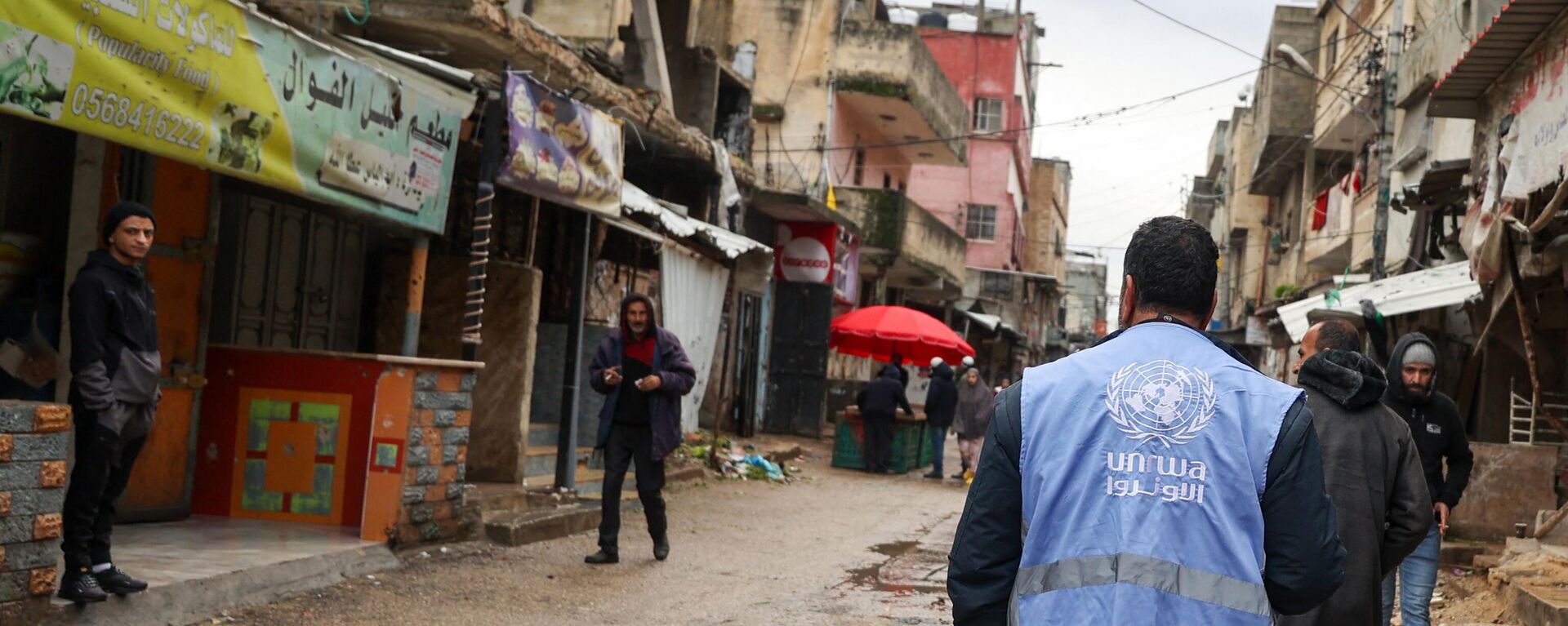 رجل يرتدي سترة تحمل شعار وكالة الأمم المتحدة لإغاثة وتشغيل اللاجئين الفلسطينيين (الأونروا) في غزة - سبوتنيك عربي, 1920, 19.02.2024