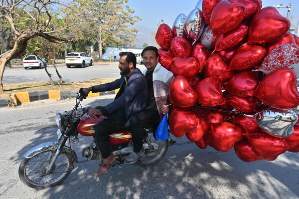 رجال يركبون دراجة بعد شراء بالونات على شكل قلوب في سوق للزهور في عيد الحب في إسلام آباد في 14 فبراير 2024. - سبوتنيك عربي