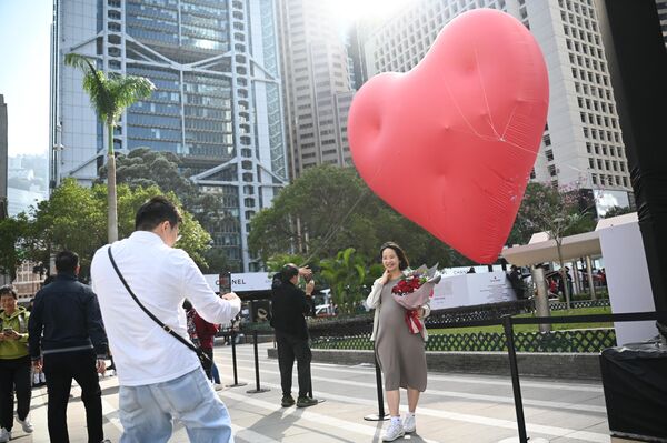 امرأة تقف لالتقاط الصور أمام قلب عملاق في عيد الحب في هونغ كونغ في 14 فبراير 2024. - سبوتنيك عربي