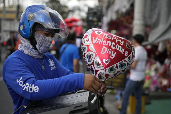 رجل يربط بالونًا على دراجته النارية خلال عيد الحب يوم الأربعاء 14 فبراير 2024، في مانيلا، الفلبين. - سبوتنيك عربي