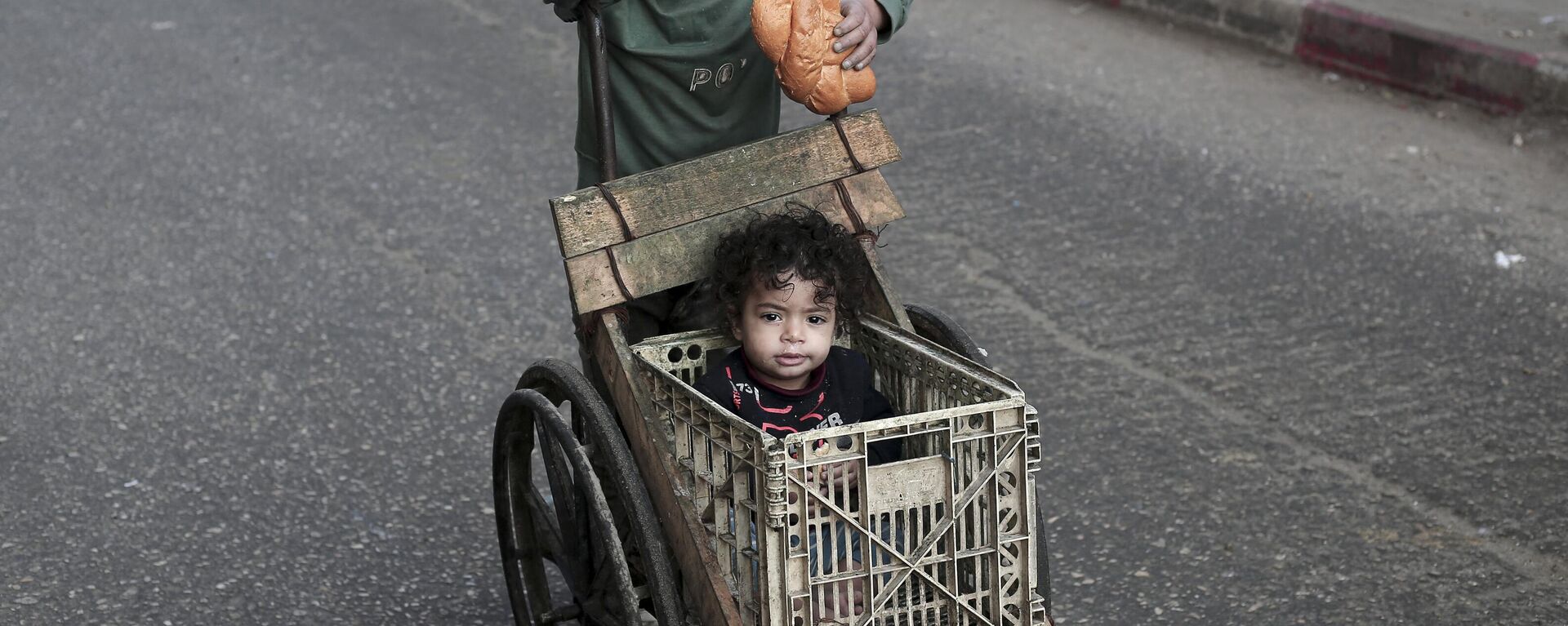 صبي يدفع طفلاً في عربة في رفح، جنوب قطاع غزة. - سبوتنيك عربي, 1920, 04.03.2024