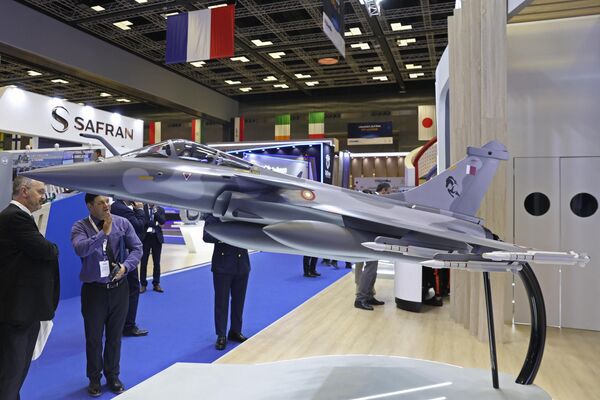 زوار ينظرون إلى نموذج لطائرة قطرية مقاتلة معروضة خلال معرض ومؤتمر الدوحة الدولي للدفاع البحري (ديمدكس 2024) في مركز قطر الوطني للمؤتمرات بالدوحة. - سبوتنيك عربي