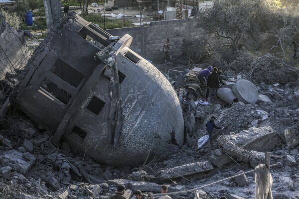 أناس يبحثون عن أشياء يمكن إنقاذها وسط أنقاض مسجد البخاري الذي دمرته الغارات الإسرائيلية في دير البلح وسط غزة في 2 مارس/آذار 2024. - سبوتنيك عربي