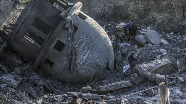 شخاص يبحثون عن أشياء يمكن إنقاذها بين أنقاض مسجد البخاري الذي دمرته غارات إسرائيلية في دير البلح وسط قطاع غزة. - سبوتنيك عربي