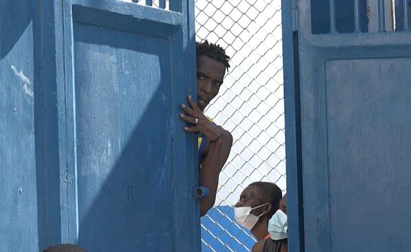 تُظهر لقطة الشاشة هذه المأخوذة من AFPTV شخصًا ينظر من خلف باب بالقرب من السجن الرئيسي في بورت أو برنس، هايتي، في 3 مارس/آذار 2024، بعد هروب عدة آلاف من السجناء. قتل ما لا يقل عن عشرة أشخاص عندما هاجم أفراد عصابة السجن الرئيسي في عاصمة هايتي، ما أدى إلى فرار عدة آلاف من السجناء. - سبوتنيك عربي