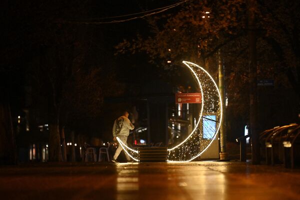 رجل يسير بجوار زينة شهر رمضان على شكل هلال في وسط مدينة بريشتينا، في اليوم الأول من شهر رمضان، كوسوفو 11 مارس 2024. - سبوتنيك عربي