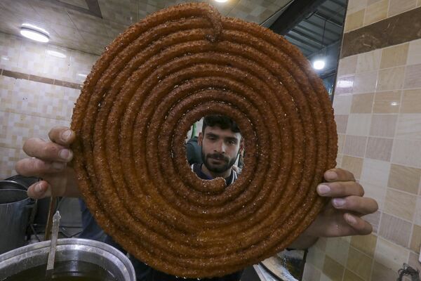 رجل يقوم بإعداد الحلويات المقلية للإفطار، في اليوم الأول من شهر رمضان في مدينة الباب شمالي سوريا، 11 مارس 2024. - سبوتنيك عربي