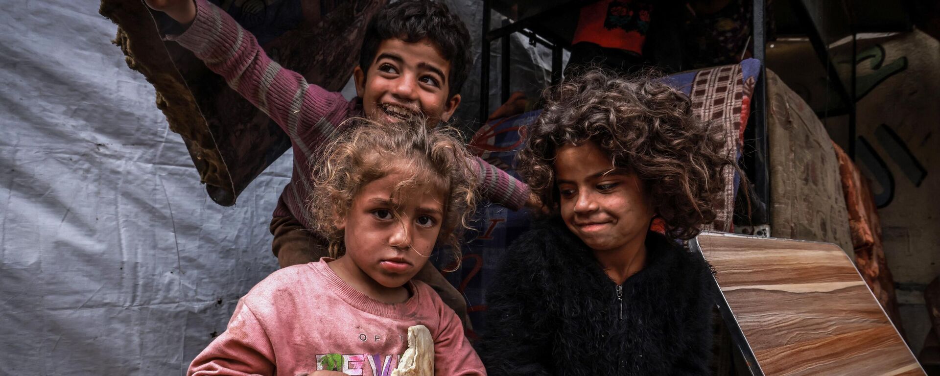 أطفال غزة - أطفال فلسطينيون نازحون يلتقطون صورًا أمام خيام مؤقتة في مخيم بجانب أحد شوارع رفح، قطاع غزة، فلسطين، في 14 مارس 2024 - سبوتنيك عربي, 1920, 16.03.2024