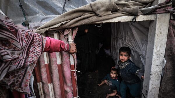 أطفال غزة - أطفال فلسطينيون نازحون ينتظرون داخل خيامهم المؤقتة في مخيم بجانب أحد شوارع رفح، قطاع غزة، فلسطين 14 مارس 2024
 - سبوتنيك عربي