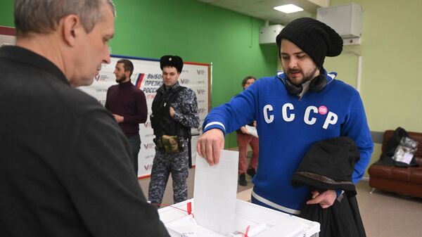 Мужчина голосует на выборах президента России на избирательном участке школы №2123 в Москве - سبوتنيك عربي