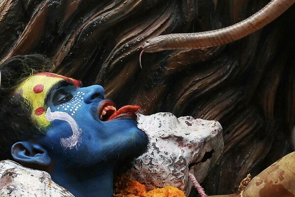 أحد المتدينين الهندوس يحمل ثعبانا بجانب وجهه خلال موكب ديني بمناسبة &quot;ماسان&quot; أو &quot;باسما&quot; هولي، والذي يتم الاحتفال به برماد المحرقة الجنائزية في فاراناسي الهندية. - سبوتنيك عربي