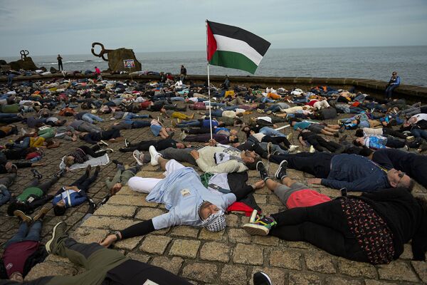 متظاهرون مؤيدون للفلسطينيين على الأرض أثناء احتجاجهم على الهجمات الإسرائيلية على غزة في سان سيباستيان شمالي إسبانيا. - سبوتنيك عربي