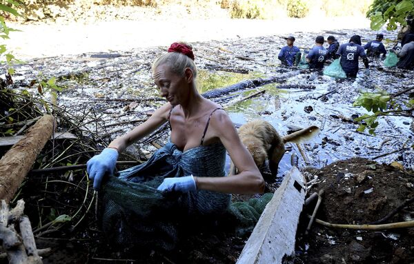 متطوعة أجنبية تجمع القمامة من نهر مغطى بالقمامة في بيكاتو الأندونيسية. - سبوتنيك عربي