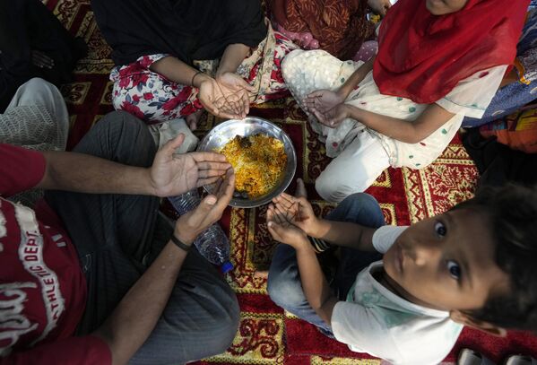 مجموعة من الصائمين يقومون بالدعاء قبل الإفطار، خلال شهر رمضان، في نقطة توزيع وجبات مجانية تديرها مجموعة خيرية، في كراتشي، باكستان، 23 مارس 2024. - سبوتنيك عربي