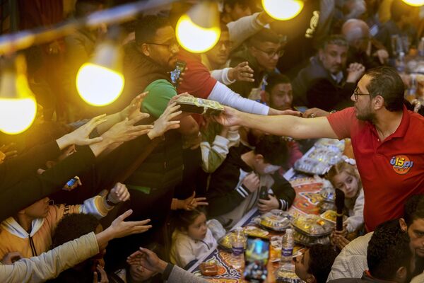 متطوع يوزع وجبات مجانية على سكان &quot;عزبة حمادة&quot; في حي &quot;المطرية&quot; بالقاهرة، خلال إفطار جماعي، خلال شهر رمضان، مصر، 25 مارس 2024. - سبوتنيك عربي