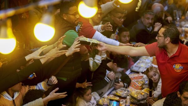 Волонтер раздает бесплатную еду во время массовой трапезы ифтар во время священного месяца Рамадан, Каир, Египет  - سبوتنيك عربي