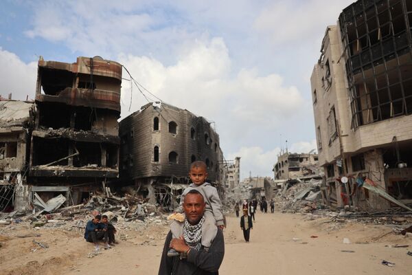 فلسطينيون يسيرون أمام المباني المتضررة في خان يونس في 8 أبريل 2024 بعد أن سحبت إسرائيل قواتها البرية من جنوب قطاع غزة، بعد ستة أشهر من الحرب المدمرة التي أشعلتها هجمات 7 أكتوبر/تشرين الأول. - سبوتنيك عربي