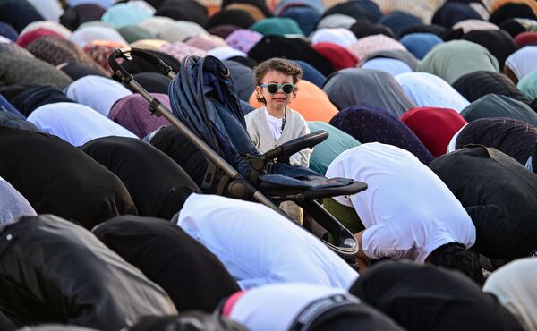 طفل واقف وينظر بينما يقوم مسلمون من رومانيا بالسجود أثناء أدائهم صلاة عيد الفطر بمناسبة نهاية شهر رمضان المبارك في ملعب دينامو في بوخارست، رومانيا، في 10 أبريل 2024. شارك نحو 2000 شخص. - سبوتنيك عربي