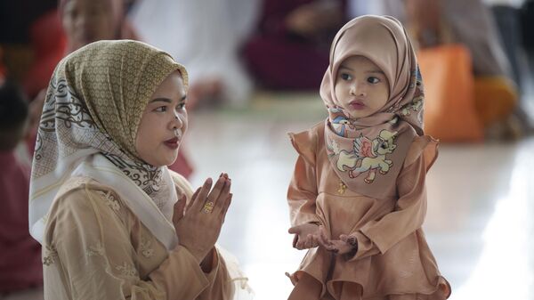 Мусульманка показывает своей дочери, как молиться, в Национальной мечети, по окончании священного месяца Рамадан, в Куала-Лумпуре, Малайзия - سبوتنيك عربي