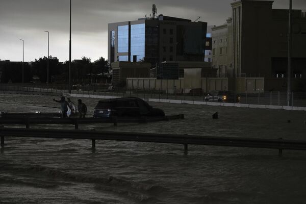 رجال يحاولون سحب سيارة من المياه الراكدة في دبي، الإمارات العربية المتحدة، الثلاثاء، 16 أبريل 2024. - سبوتنيك عربي