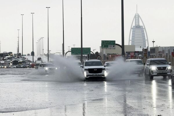 سيارة دفع رباعي على طريق يظهر فيه فندق برج العرب الفاخر في دبي. - سبوتنيك عربي