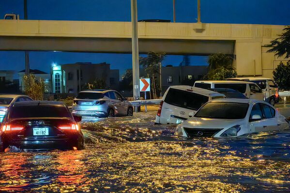 سيارات تسير على طول شارع غمرته المياه بعد هطول أمطار غزيرة في إمارة دبي، الإمارات العربية المتحدة. - سبوتنيك عربي