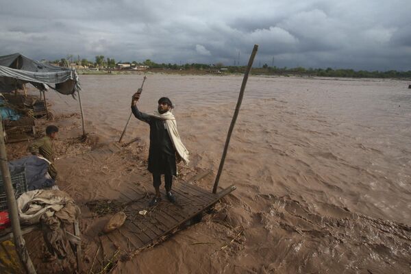 رجل يلتقط صورة شخصية على ضفة نهر فاض بعد هطول أمطار غزيرة على مشارف بيشاور، باكستان. - سبوتنيك عربي