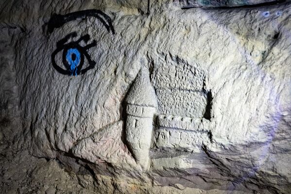 صورة تظهر عينًا مرسومة على جدار وقلعة منحوتة في الحجر في سراديب الموتى المحرمة في باريس. - سبوتنيك عربي