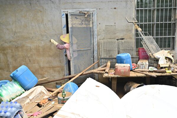 عامل يقوم بتنظيف أحد المباني بعد أن غمرت الأمطار الغزيرة المنطقة في قرية شاتانغ، في تشينغيوان، في مقاطعة قوانغدونغ الشمالية، في 24 أبريل/ نيسان 2024. - سبوتنيك عربي