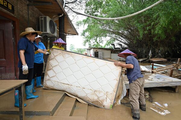 عمال يحملون مرتبة من غرفة فندق، بعد أن غمرت الأمطار الغزيرة المنطقة في قرية شاتانغ، في تشينغيوان، في مقاطعة قوانغدونغ الشمالية، في 24 أبريل 2024. - سبوتنيك عربي