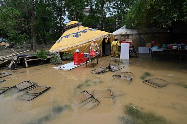 الكراسي مغمورة بالمياه بينما يجمع العمال الأشياء بعد أن غمرت الأمطار الغزيرة المنطقة في قرية شاتانغ، في تشينغيوان، في مقاطعة قوانغدونغ الشمالية، في 24 أبريل 2024. - سبوتنيك عربي