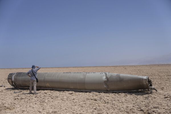 مصور صحفي ينظر إلى جزء من الصاروخ البالستي، الذي تم اعتراضه وسقط بالقرب من البحر الميت في إسرائيل. - سبوتنيك عربي