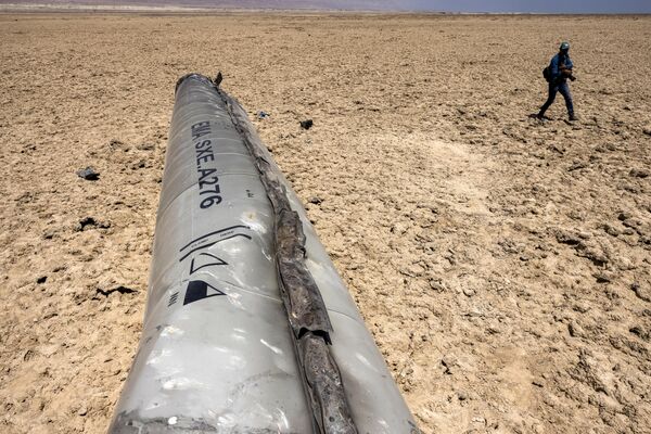 مصور يسير بالقرب من بقايا الصاروخ الذي سقط بالقرب من البحر الميت، بعد أسبوع من القصف الصاروخي الذي أطلقته إيران، في 13 أبريل 2024. - سبوتنيك عربي