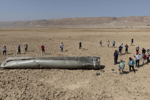أشخاص يتجمعون حول أحد مكونات صاروخ باليستي تم اعتراضه وسقط بالقرب من البحر الميت في إسرائيل. - سبوتنيك عربي