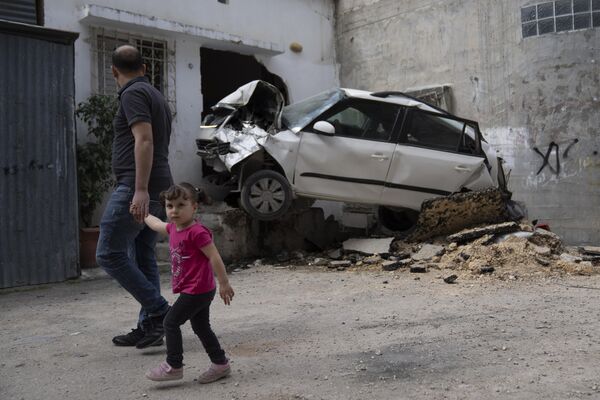 فلسطينيون يتفقدون السيارة المتضررة في مخيم نور شمس للاجئين في طولكرم في الضفة الغربية، الأحد 21 أبريل 2024. - سبوتنيك عربي