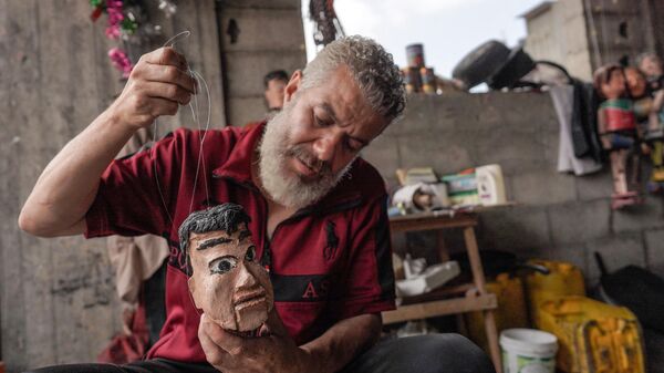 Махди Карира демонстрирует одну из своих кукол, сделанных из консервных банок, в своей мастерской в ​​Дейр-эль-Балахе, в центральном секторе Газы - سبوتنيك عربي