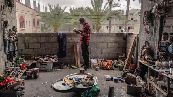 الفلسطيني مهدي كريرة يعمل على دمية مصنوعة من علب لمعلبات القديمة في ورشته في دير البلح وسط قطاع غزة، في 27 أبريل 2024 - سبوتنيك عربي