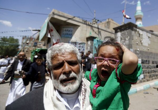 رجل مسن يهرب بطفلة من مكان الانفجار في اليمن اليوم الجمعة 20 مارس/ آذار 2015. - سبوتنيك عربي