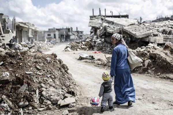 امرأة سورية كردية مع طفل على انقاض مدينة عين العرب (كوباني) - سبوتنيك عربي